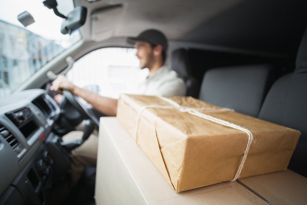 Delivery driver driving van with parcels on seat outside the warehouse-1
